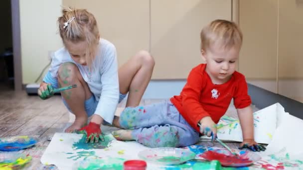 Adorabile carino caucasico fratellini biondi bambini godono di divertirsi insieme con la madre pittura pennello e palmo a casa all'interno. Allegro felice bambini sorridente disegno capolavoro arte foto — Video Stock