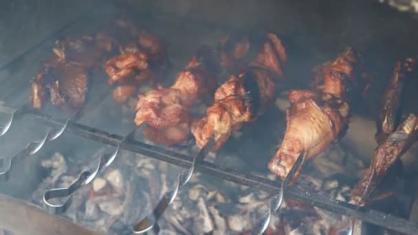 Vista de perto do churrasco braseiro cozinhando peru grande ou perna de carne de frango em espetos metálicos incendiados na queima de carvão com chama de fogo e fumaça. tradicional leste europeu bbq festa casa quintal comida — Vídeo de Stock