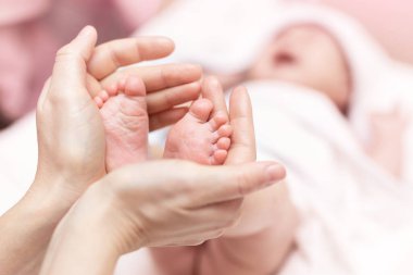 Anne yeni doğmuş bebek ayaklarını elinde tutuyor. Annem banyo yaptıktan sonra bebeğe bakıyor. Ebeveynler çocuk bakıcılığı. Çocuk sağlığı ve mutlu bir aile.