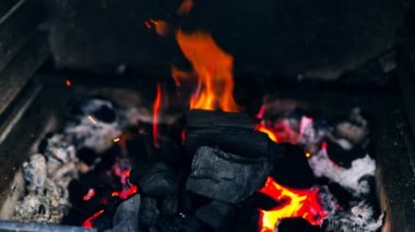 Kırmızı turuncu kıvılcımlarla Brezilya 'da yanan siyah ahşap kömürlerin ağır çekimde yanması ve dışarıdaki metal brazier' da duman çıkması. Barbekü partisi pişirme arka planı
