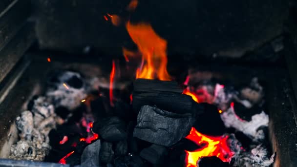 Медленное движение горящих черных древесных углей в жаровне с красно-оранжевыми пламенными искрами и дымом на металлической жаровне на улице. Кулинарный фон барбекю — стоковое видео