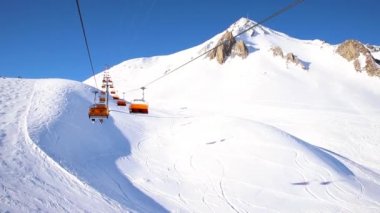 Aydınlık güneşli bir günde dağlık dağlarda kayak kaldırma halatı. Kayak koltuğu kaldırma kablosu insanların kayak ve snowboard yapmaktan hoşlandığı bir yol. Manzaralı, yokuş aşağı geniş bir manzara..