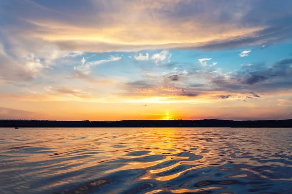 Güzel, dramatik, parlak, parlak, mavi ve kırmızı, sıcak, sıcak, akşam saatlerinde gölün veya nehrin dalgalı su yüzeyine yansıyan bulutlu manzara manzarası. Arka planda Ufuk Sahil Çizgisi.