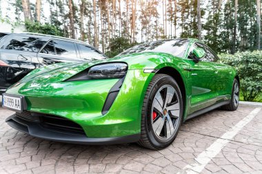 Kyiv, Ukrayna - 6 Eylül 2020: Mamba yeşil metalik renkte yeni elektrikli sıfır emisyonlu Porsche Taycan turbo sonbahar günü ormanda şehir caddesine park edildi.