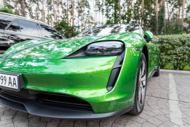 Kyiv, Ukrayna - 6 Eylül 2020: Mamba yeşil metalik renkte yeni elektrikli sıfır emisyonlu Porsche Taycan turbo sonbahar günü ormanda şehir caddesine park edildi.