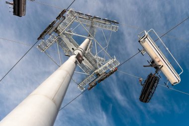 Güneşli bir günde tepedeki dağlık dağ eteklerinde kayak asansörü kavşağında kavşağı olan büyük metal sütunların altında. İnsanların kayak yapmayı sevdiği teleferik kablosu..