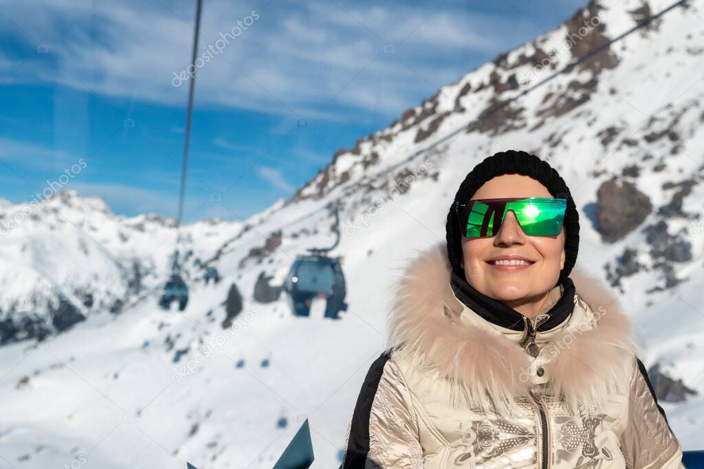 Young adult beautiful happy attractive caucasian smiling woman enjoy ascent sitting inside ski lift gondola cable car against skiing resort panorama breathtaking view. Winter travel welcome concept.