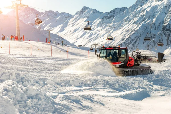 Red ratrack moderne de chat des neiges avec chasse-neige machine de toilettage des neiges préparant piste de ski piste colline à ski alpin station d'hiver Ischgl en Autriche. Machinerie lourde matériel de montagne piste véhicule — Photo