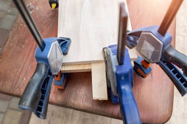 Yapıştırmadan sonra tahta el yapımı kutuya kelepçe takmak. El sanatları atölyesinde farklı keskiler, matkaplar ve kalemler. Ahşap tezgahtaki DIY enstrümanları. İşyeri organizasyon düzenlemesi