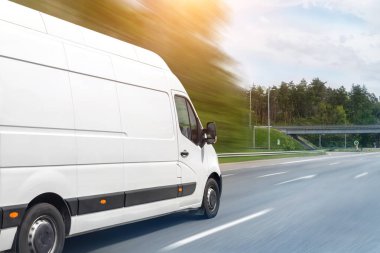 Beyaz modern teslimat küçük kargo kargo kargo minibüsü şehir merkezine giden otoyolda hızla ilerliyor. İşletme dağıtımı ve lojistik ekspres hizmeti. Güneşli bir günde otoyolda giden mini otobüs..