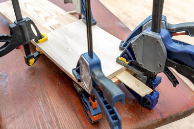 Yapıştırmadan sonra tahta el yapımı kutuya kelepçe takmak. El sanatları atölyesinde farklı keskiler, matkaplar ve kalemler. Ahşap tezgahtaki DIY enstrümanları. İşyeri organizasyon düzenlemesi.