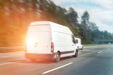 Beyaz modern teslimat küçük kargo kargo kargo minibüsü şehir merkezine giden otoyolda hızla ilerliyor. İş dağıtımı ve lojistik ekspres hizmeti. Güneşli bir günde otoyolda giden mini otobüs..