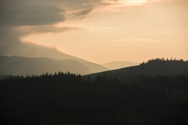 Fırtına bulutları dağların ve gün batımı sırasında orman.