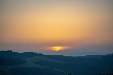 Dağ ve günbatımı bulutlar ile arka plan üzerinde çayır