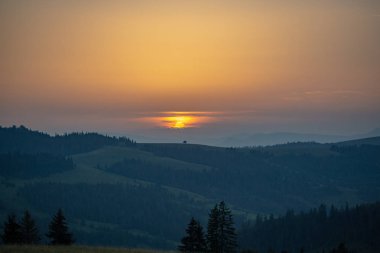 Dağ ve günbatımı bulutlar ile arka plan üzerinde çayır