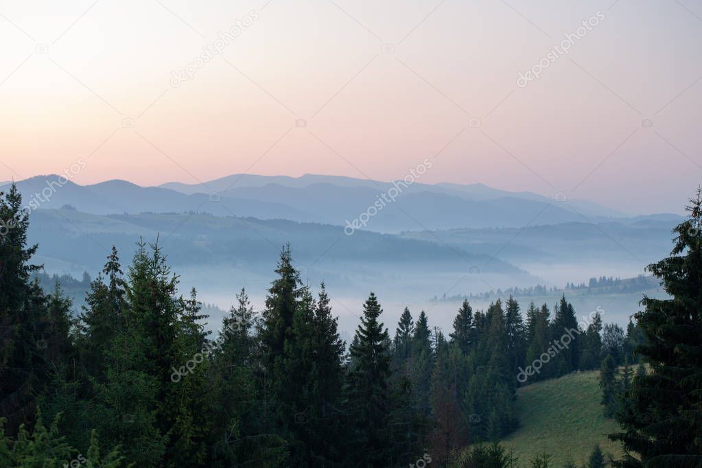 view of a valley in a beautiful early morning with fog between mountains
