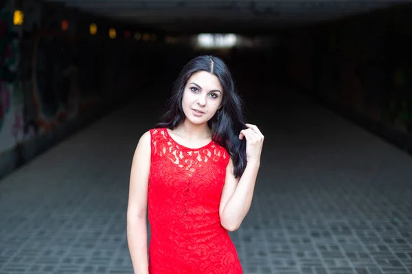 Schöne Mädchen in einem roten Kleid auf dem Hintergrund einer U-Bahn-Kreuzung.. — Stockfoto