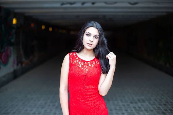 Schöne Mädchen in einem roten Kleid auf dem Hintergrund einer U-Bahn-Kreuzung.. — Stockfoto