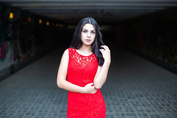 Schöne Mädchen in einem roten Kleid auf dem Hintergrund einer U-Bahn-Kreuzung.. — Stockfoto