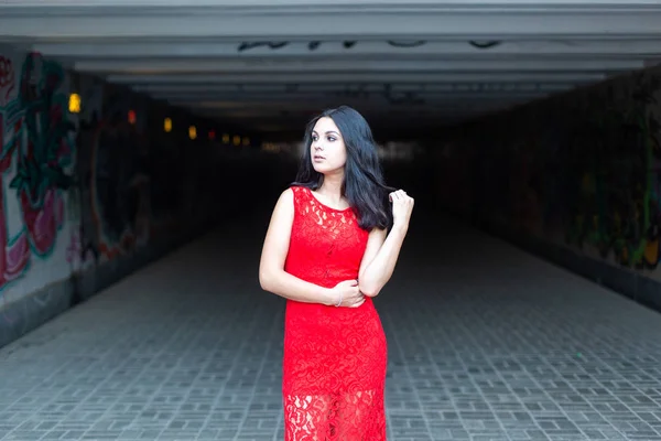 Bella ragazza in un vestito rosso su uno sfondo di una traversata sotterranea .. — Foto Stock