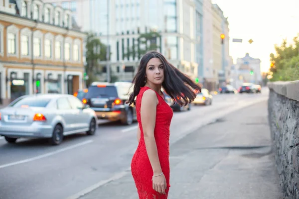 Hermosa chica en un vestido rojo está de pie cerca de la carretera . —  Fotos de Stock