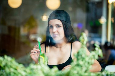 Güzel bir genç kız portresi. Yalnız bir kafede oturur ve kulaklıklar müzik dinler. Pencereden ateş.