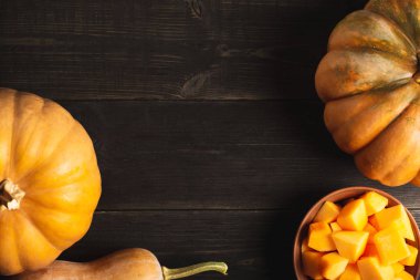 Farklı boyut ve bir tabak kabak dilimleri siyah ahşap zemin ile bütün kabak bir çerçeve. Mutfak havlusu. Uzay kopyalayın. Üstten görünüm.