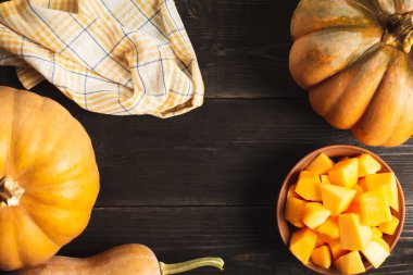 Farklı boyut ve bir tabak kabak dilimleri siyah ahşap zemin ile bütün kabak bir çerçeve. Mutfak havlusu. Uzay kopyalayın. Üstten görünüm.