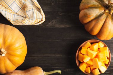 Farklı boyut ve bir tabak kabak dilimleri siyah ahşap zemin ile bütün kabak bir çerçeve. Mutfak havlusu. Uzay kopyalayın. Üstten görünüm.