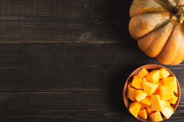 Büyük iştah açıcı bütün kabak ve bir tabak kabak dilimleri siyah ahşap zemin ile. Uzay kopyalayın. Üstten görünüm.