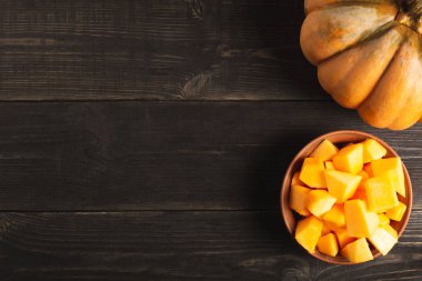 Büyük iştah açıcı bütün kabak ve bir tabak kabak dilimleri siyah ahşap zemin ile. Uzay kopyalayın. Üstten görünüm.