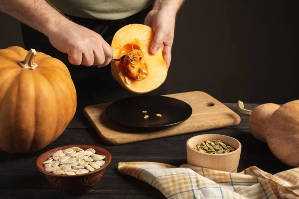 El cocinero separa el grano de la calabaza cortada por la mitad . — Foto de Stock