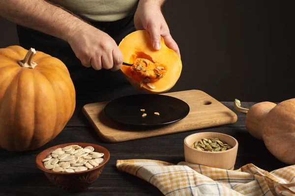 El cocinero separa el grano de la calabaza cortada por la mitad . — Foto de Stock