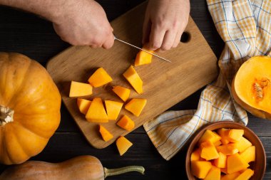 Aşçı pişirme için parçalar halinde kabak keser. Ahşap bir siyah masa üzerinde çeşitli boyutları ve şekilleri, bir bulaşık bezi ve bir kase dilimlenmiş kabak kabak yalan. Üstten görünüm.