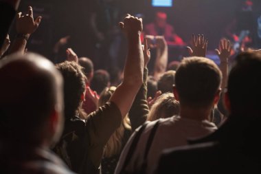 Bir konser kalabalık bir gece kulübünde ışıklı bir sahne önünde siluetleri.