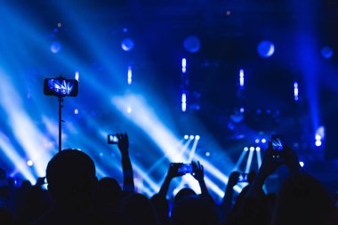 Kalabalık seyirci akıllı ellerinde bir konserde siluetleri.