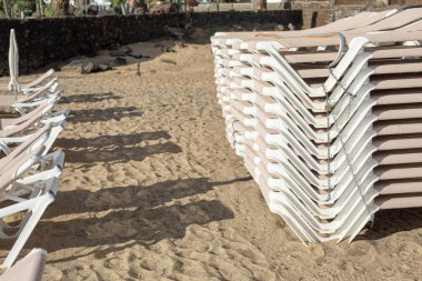 Plaj sandalyeleri Costa Teguise kumlu bir plaj üzerinde bir yığın. Adası Lanzarote, İspanya.