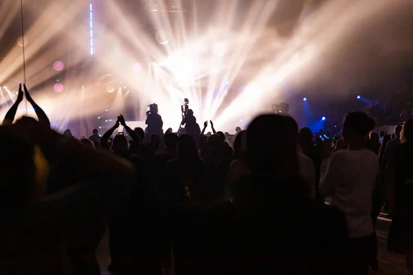 コンサートの群集とカメラマンを舞台に明るく、カラフルな光線の背景のシルエット. — ストック写真