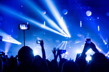 Kalabalık seyirci akıllı ellerinde bir konserde siluetleri.