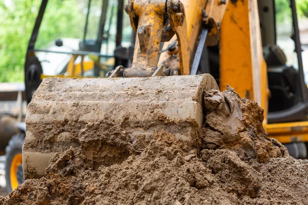 Excavator bucket pours ground. Repair work plumbing. Royalty Free Stock Photos