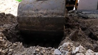 Ekskavatör kovası zemin döker. Bir konut binasının avlusında onarım çalışmaları sıhhi tesisat.