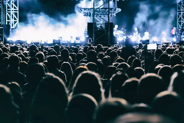 Konser kalabalığı büyük sahnede rock grubu performansını izliyor.