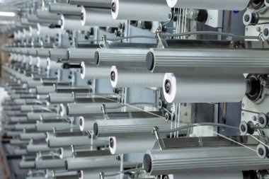 Fabrika ekipmanları perspektifte. Kumaş dokumak için polipropilen ipliklerle dolu sıralar. Otomatik makine. Kimse..