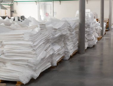 Yeni beyaz polipropilen çantaların müşteriye gönderilmeye hazır olduğu bir fabrika deposu..
