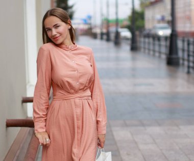 Elbise giyip sokaklarda poz veren güzel genç bir kadın.