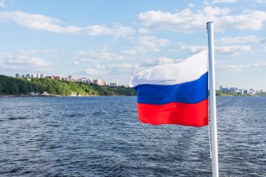 Nehrin arka planında Rus bayrağı, kıyı ve gökyüzü
