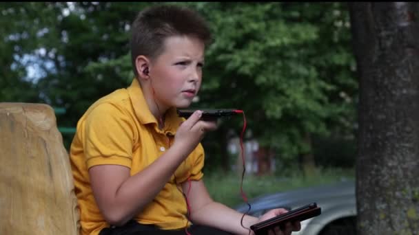 Chlapec s telefonem a tabletem ve sluchátkách. — Stock video