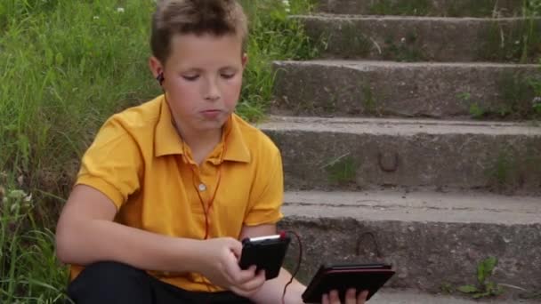 Băiatul folosește două gadget-uri simultan . — Videoclip de stoc