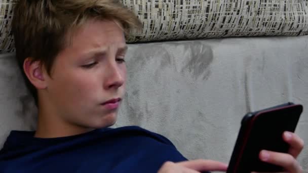 Il ragazzo fa i compiti con l'aiuto di un gadget elettronico. — Video Stock