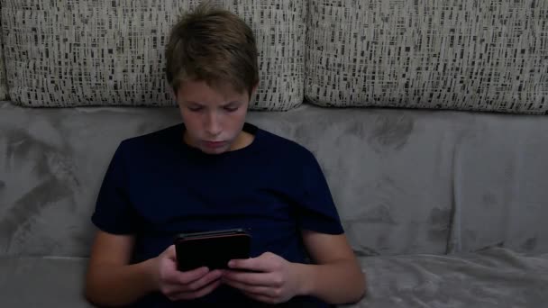 Ragazzo sul divano e legge un e-book. — Video Stock